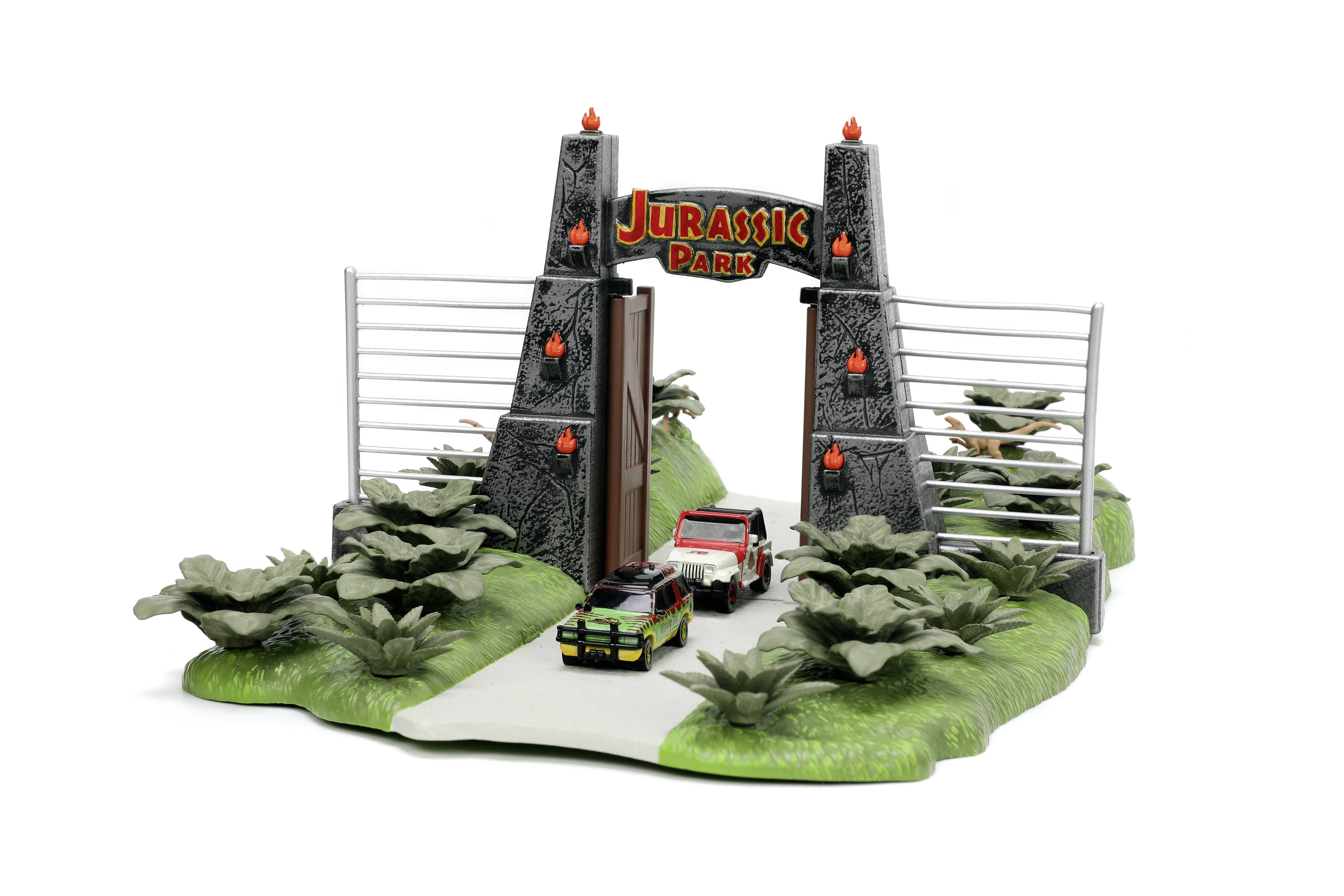 Minijaturni model ulaza u 'Jurassic Park' s dva vozila na cesti, okružen biljkama i ogradama.