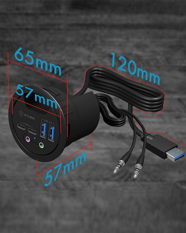 Crna stolna utičnica s USB priključcima i audio portovima, pokraj koje se nalazi kabel s USB utikačem. Dimenzije: 65 mm promjera, 57 mm dubine, 120 mm duljine kabela.