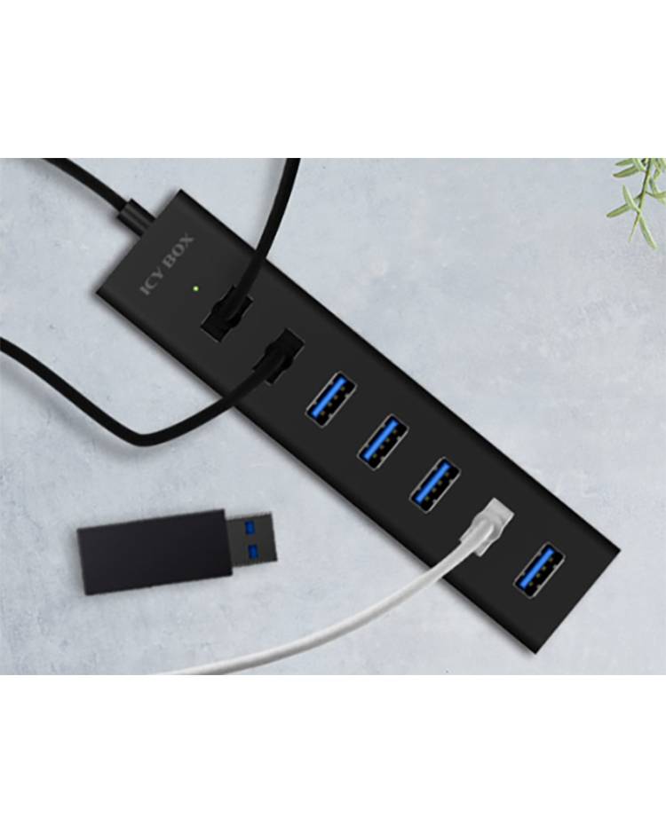 Crni USB hub s pet priključaka, na kojem su spojena tri kabela; USB stick leži pored njega. Vidljiva tekstura površine.