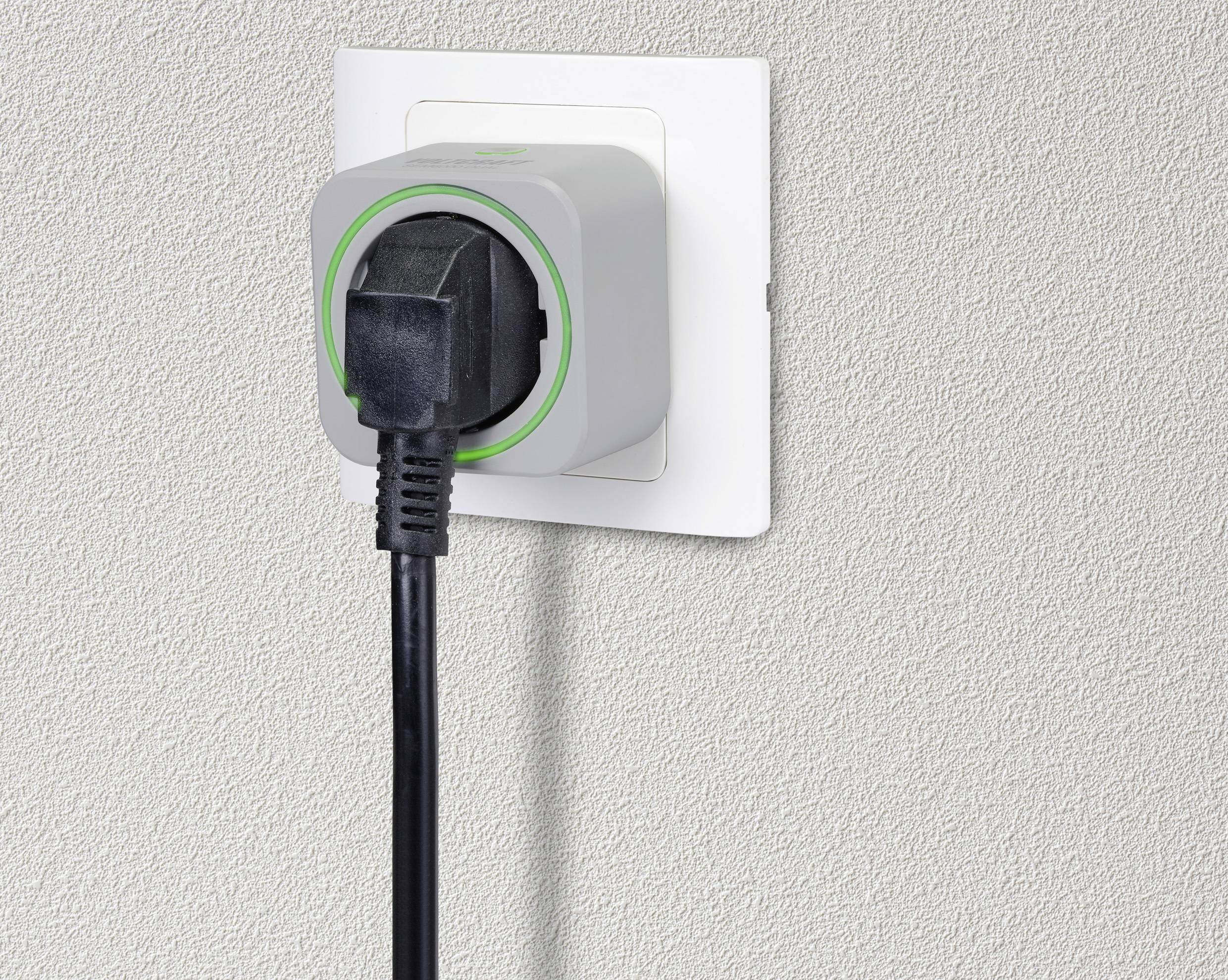 Utikač u bijeloj zidnoj utičnici s jednm sivim adapterom koji je obrien zelenim svjetlom.
