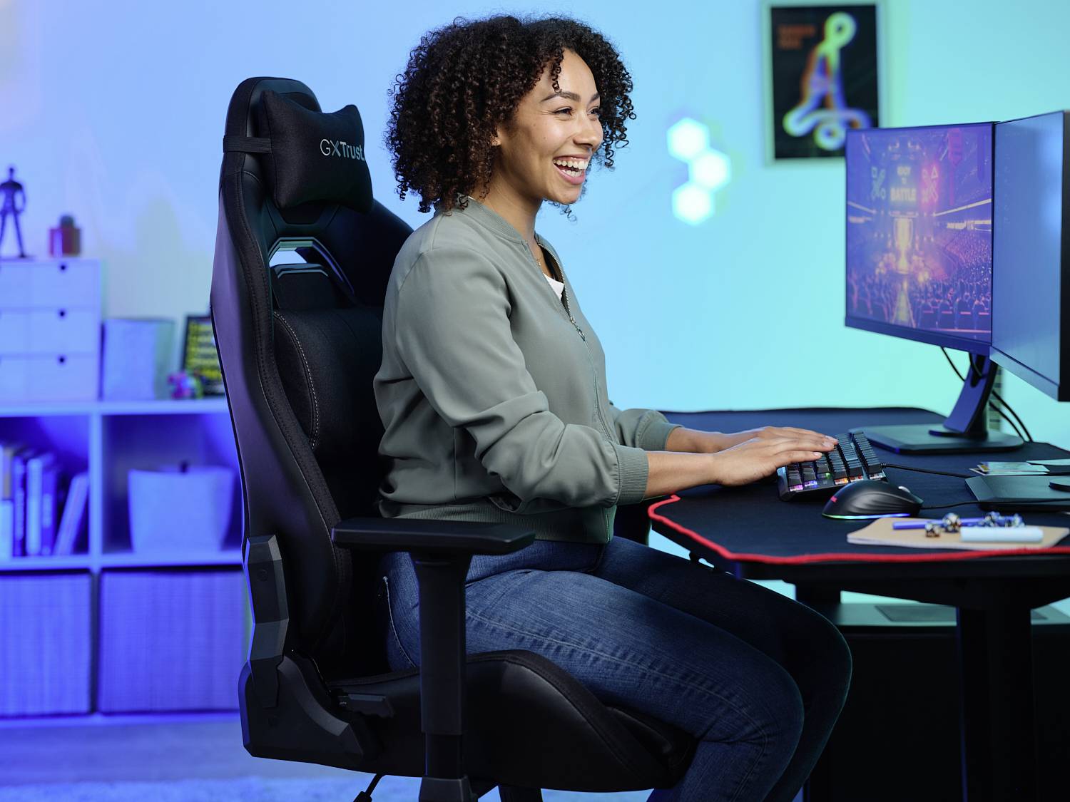 Osoba sjedi za stolom i radi na računalu, djeluje koncentrirano i zadovoljno; u pozadini su šarena svjetla.