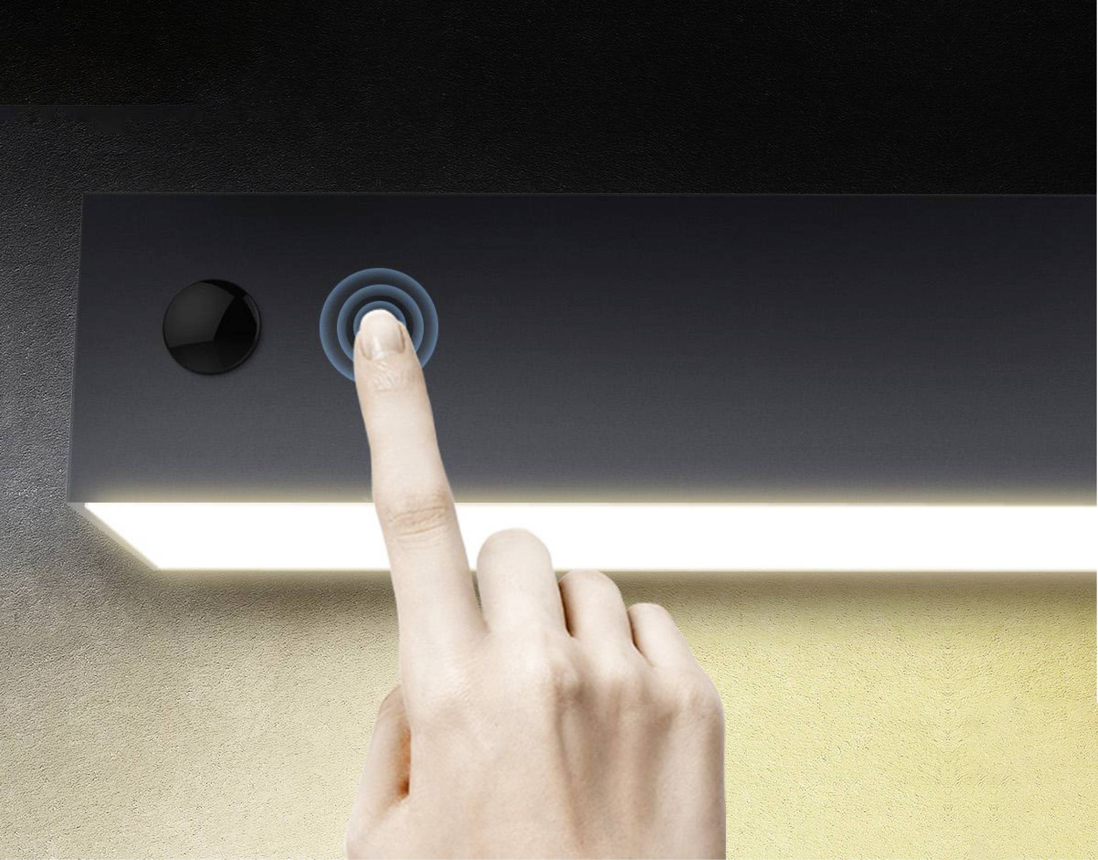 Jedna ruka pritišće senzorski gumb pravokutne, svijetleće lampe za njezinu aktivaciju ili deaktivaciju.