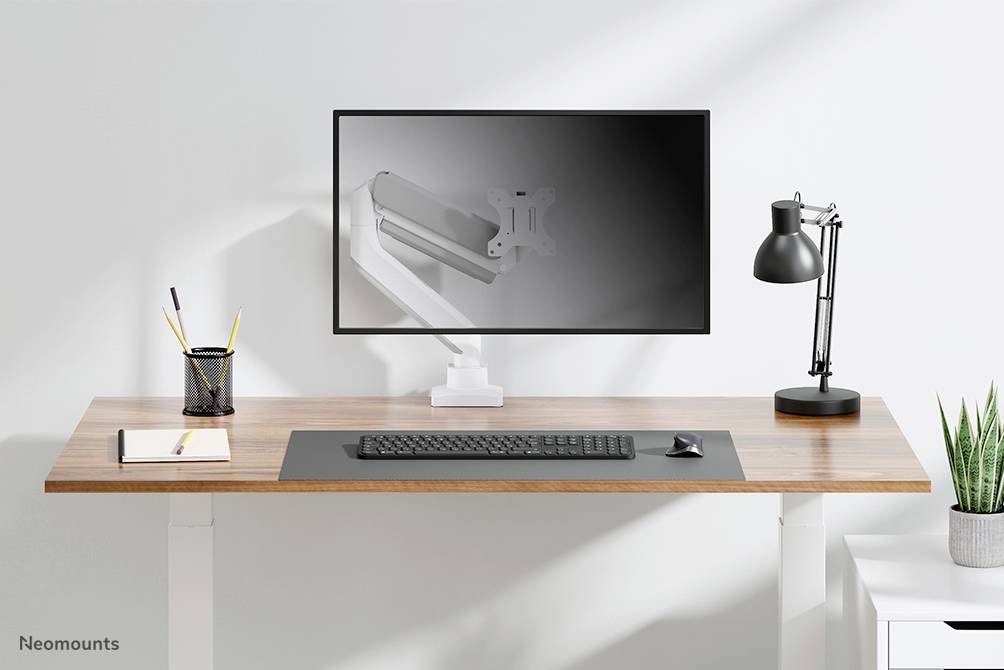 Moderan radni stol s monitorom i lampom, tipkovnicom, bilježnicom i držačem olovaka. Na zaslonu je prikazan monitorski nosač.