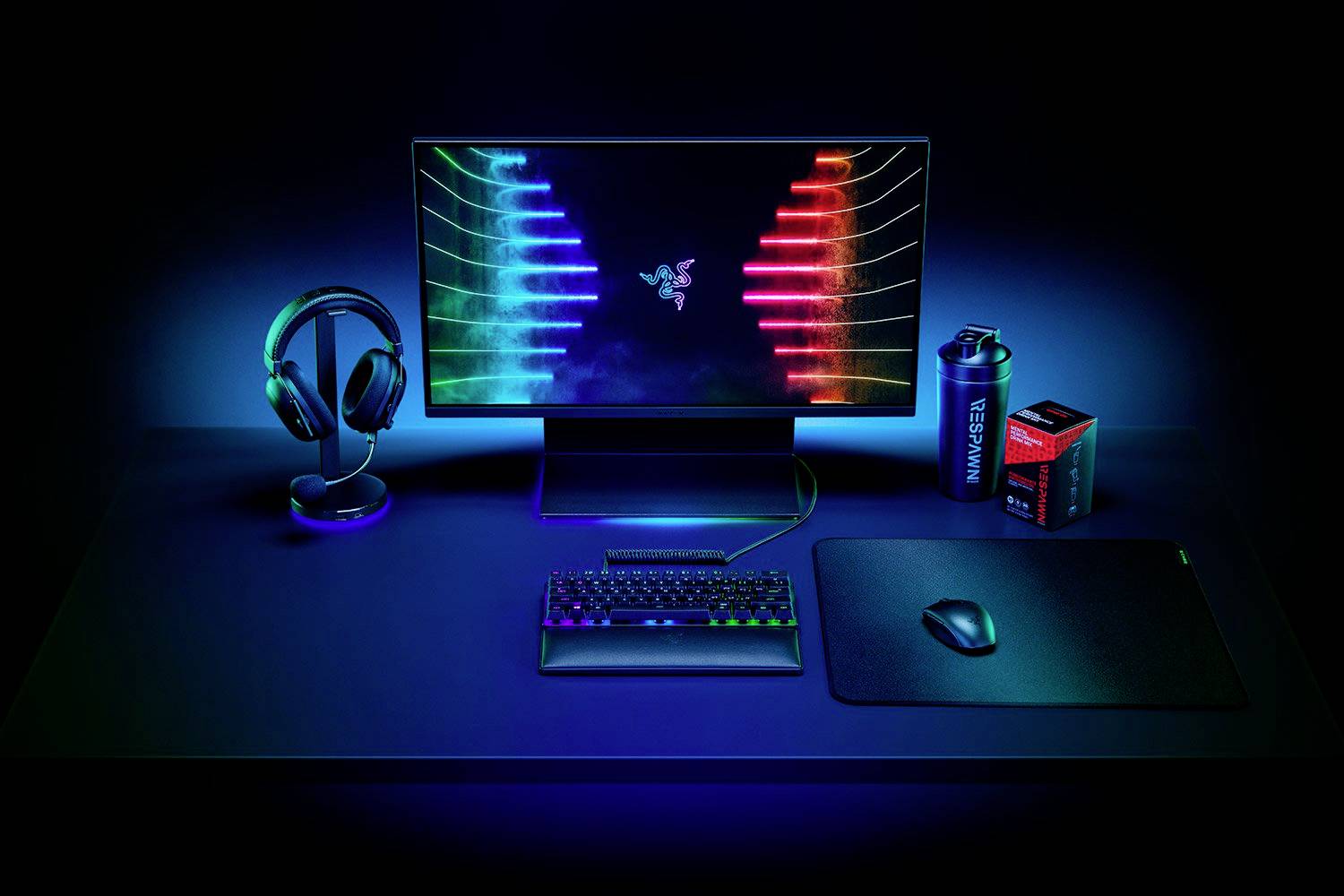 Radni stol s RGB osvjetljenjem gaming opreme: Monitor sa sjajnom pozadinom, tipkovnica, miš, slušalice i boca vode.