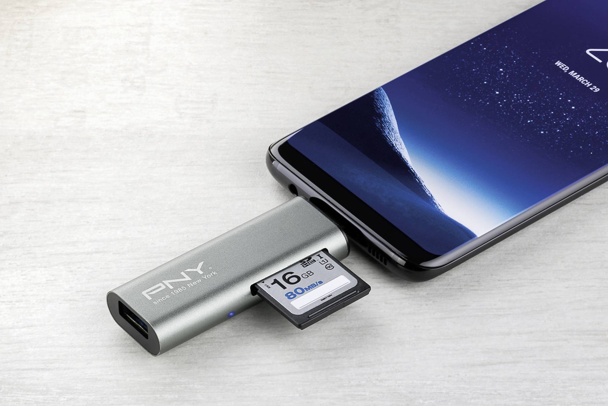 Pametni telefon je spojen s adapterom koji sadrži SD karticu. Na SD kartici piše '16 GB'.