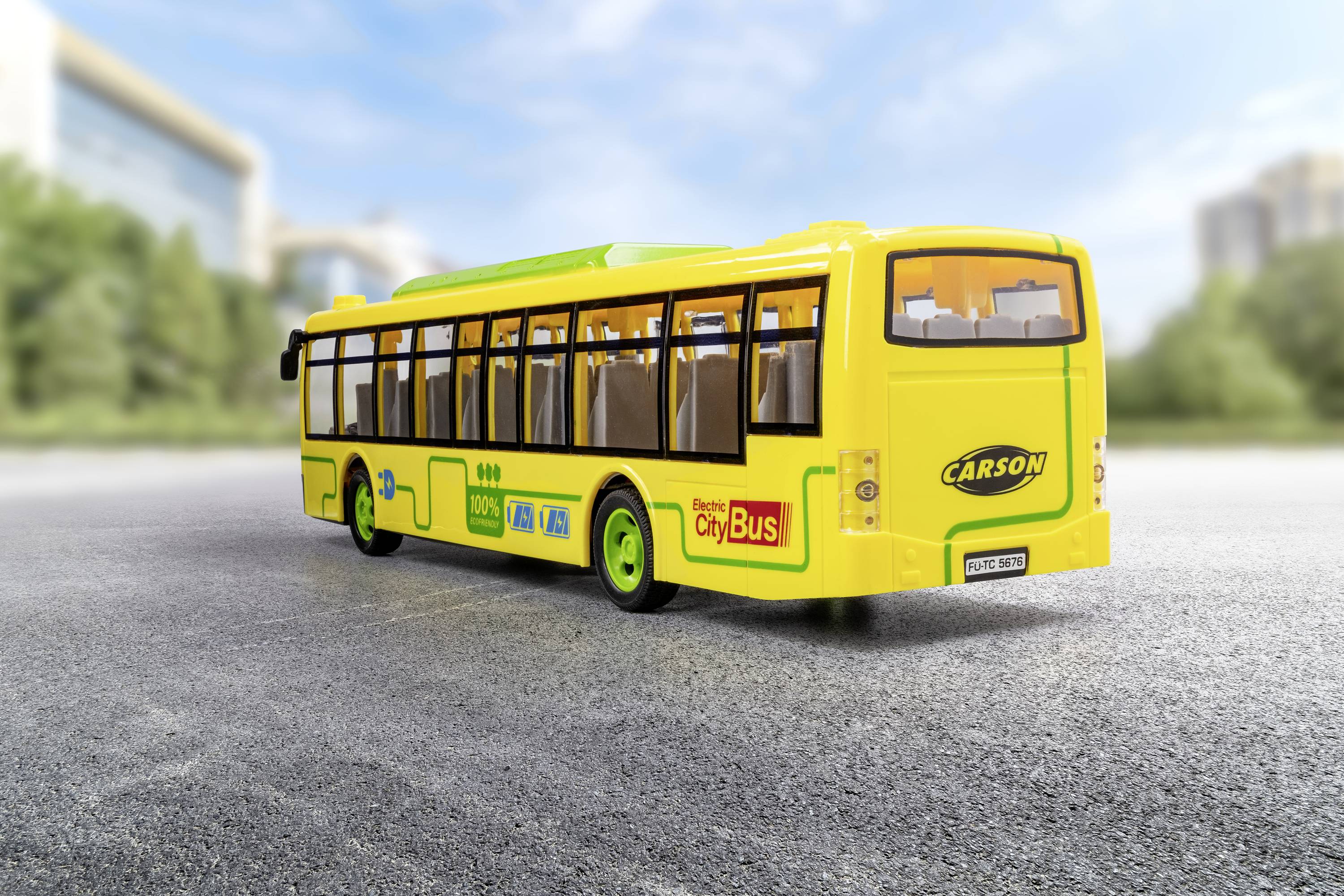 Žuti autobušić za igru s naljepnicama stoji na cesti. U pozadini se nejasno naziru zgrade i stabla.