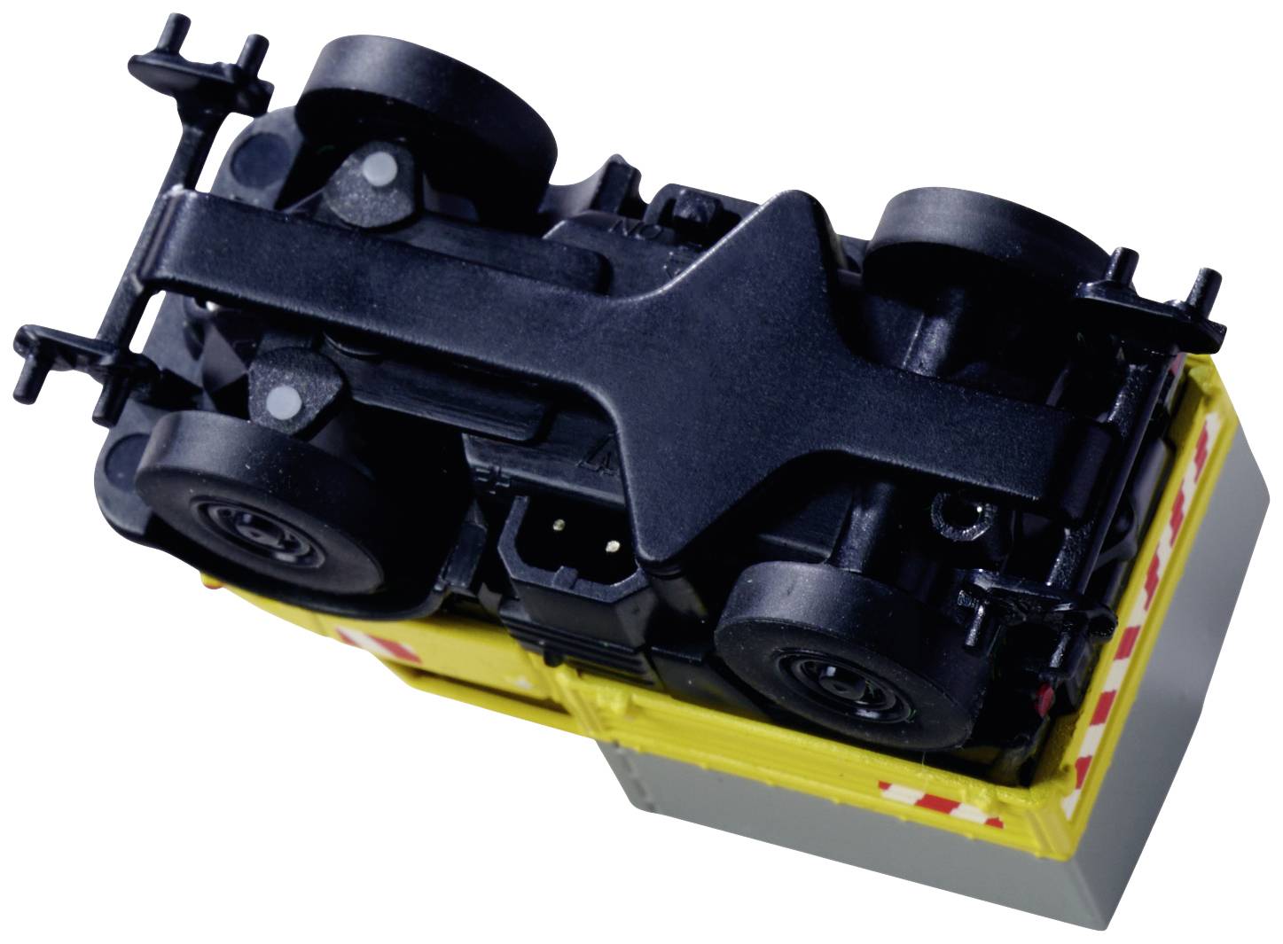 Igračka kamion položena na bok, prikazuje donju stranu i kotače. Pretežno je žuta boja s crnim elementima.