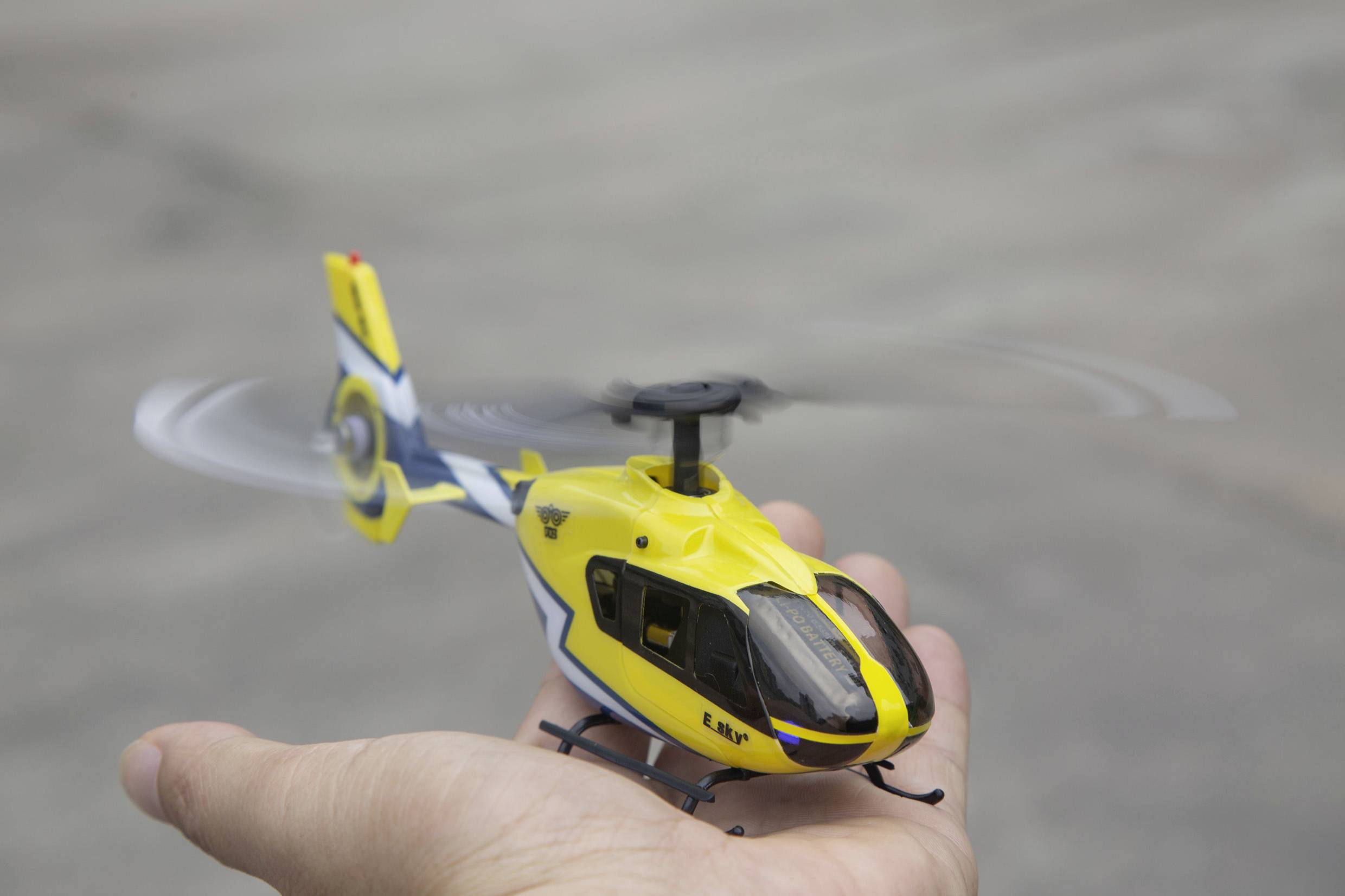 Jedna osoba drži mali model žutog helikoptera u ruci, kao da leti.
