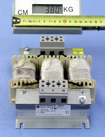 Transformator s tri namotaja na metalnom kućištu. Digitalna vaga prikazuje '3,80 KG'. Mjerna vrpca je razapeta preko gornje strane.