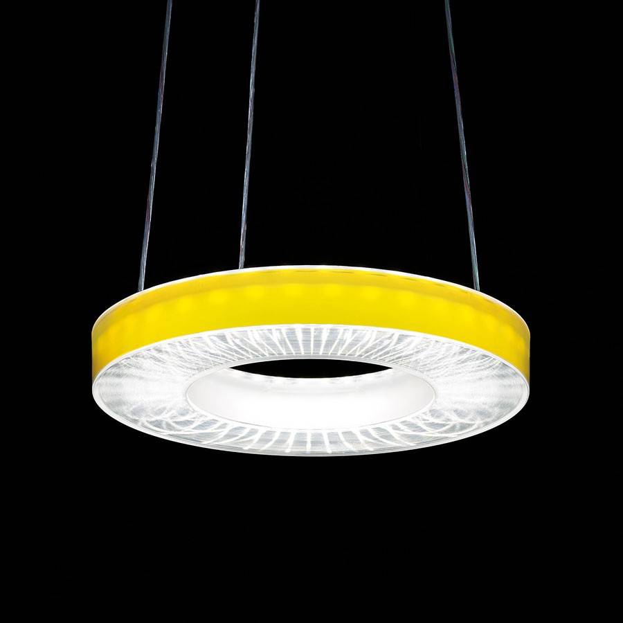Okrugla, žuta stropna lampa visi na crnim kabelima ispred crne pozadine. Odašilje jak, bijeli svijet.
