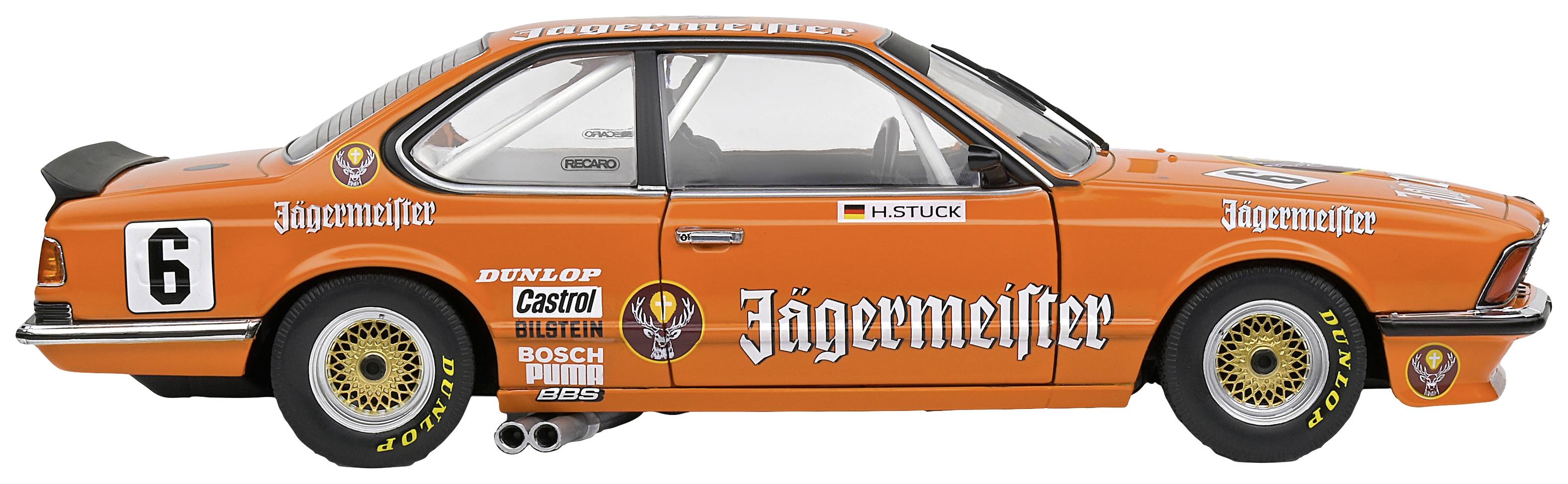 Trkaći automobil u bočnom profilu u jarko narančastoj boji sa natpisom 'Jägermeister'. Dekorativni logotipovi i startni broj 6 na vratima.