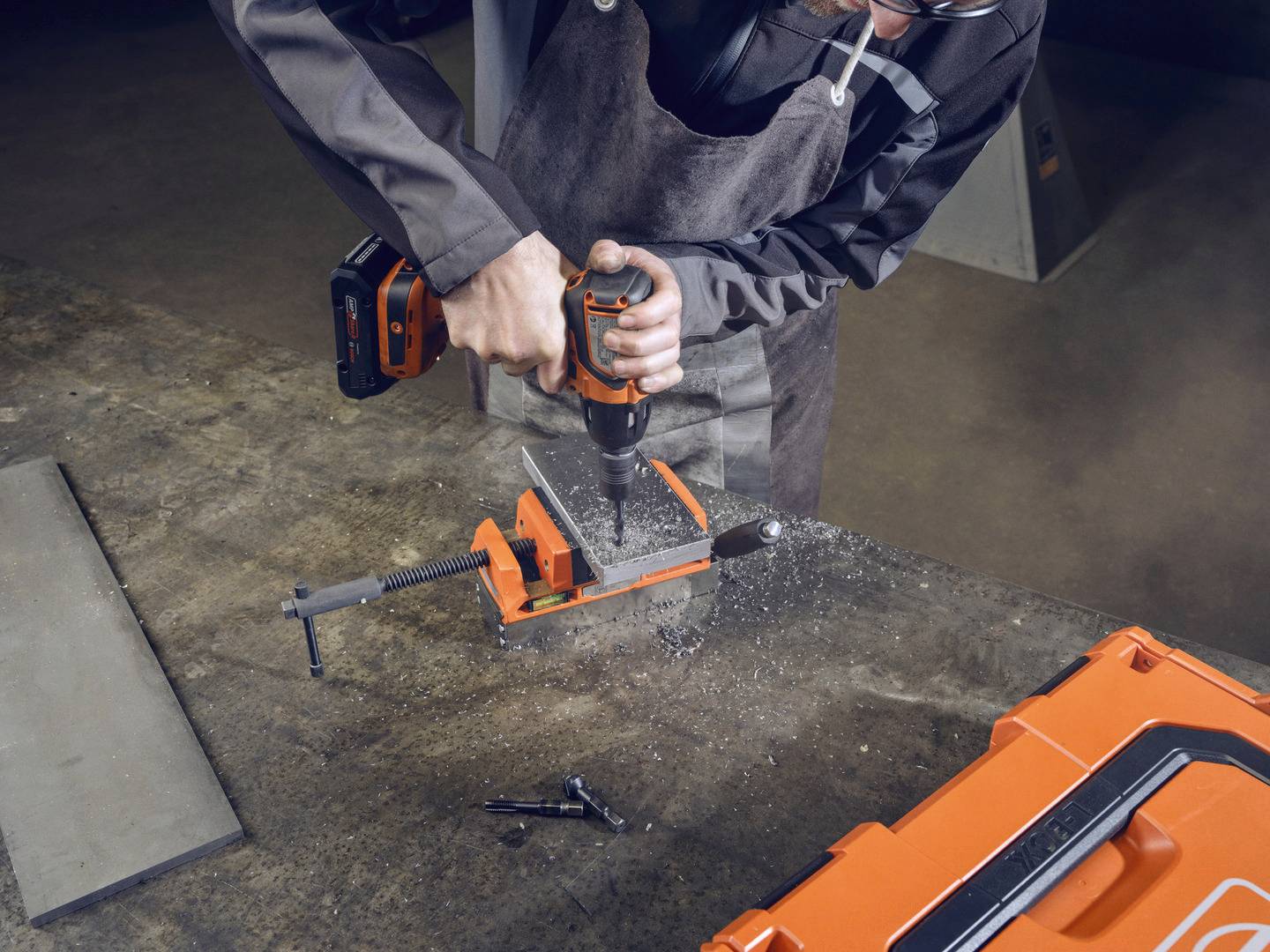 Jedna osoba bušilica električno buši rupu u komadu metala koji je učvršćen u stezaljci.