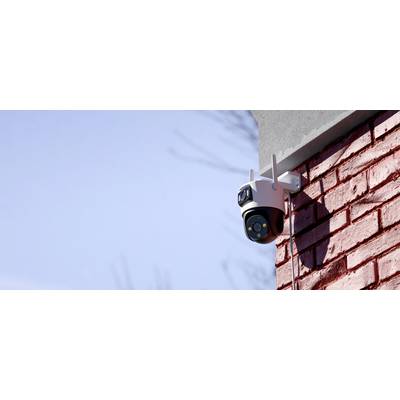 Sigurnosna kamera instalirana na crvenoj opečnoj zidu, usmjerena udesno; plavo nebo u pozadini.