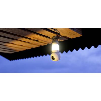 Sigurnosna kamera s integriranom lampom postavljena je ispod drvenog krova i osvjetljava prostor u sumrak.