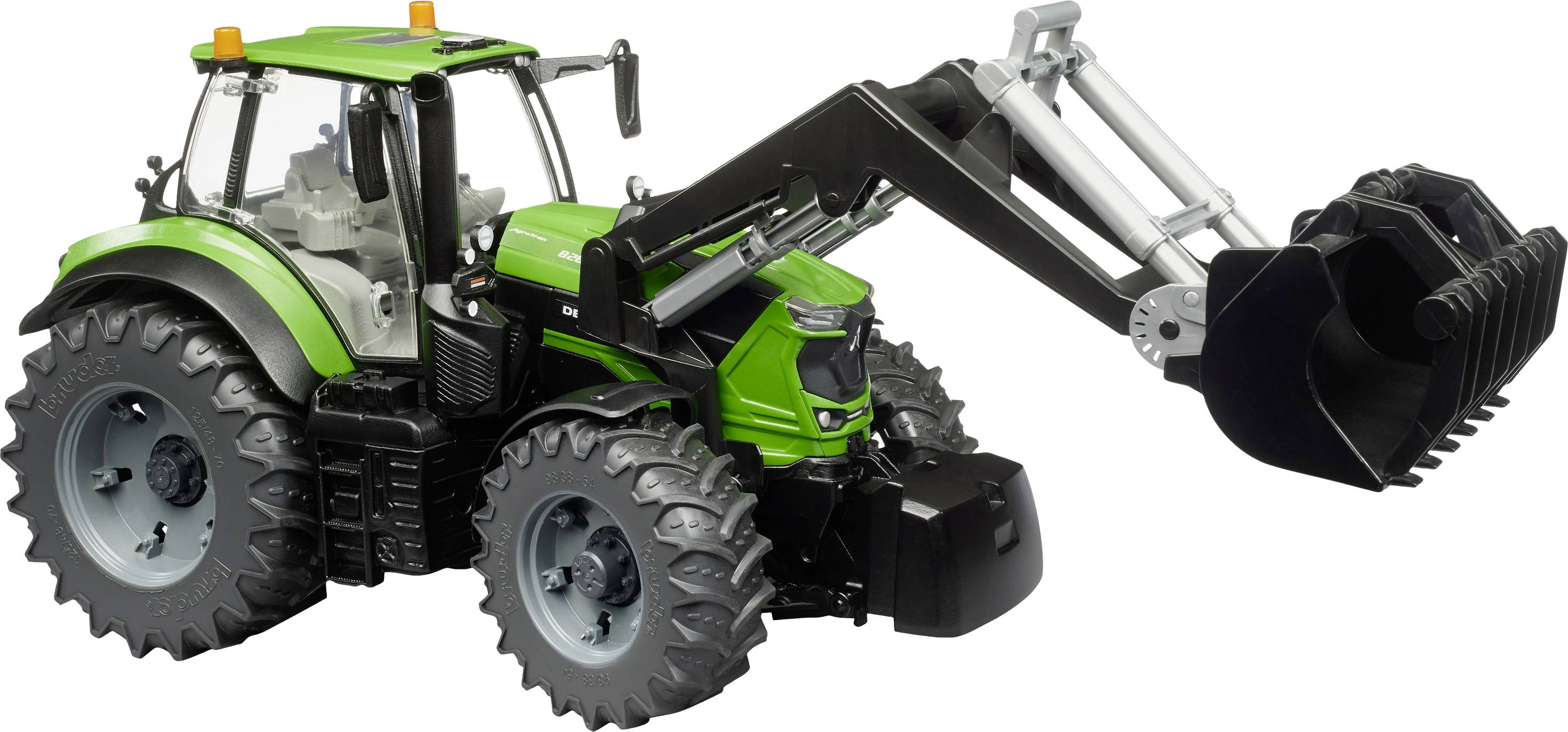 Zeleni traktor s prednjim utovarivačem stoji sa strane. Utovarivač je podignuo, a gume su velike i krupno profilirne.