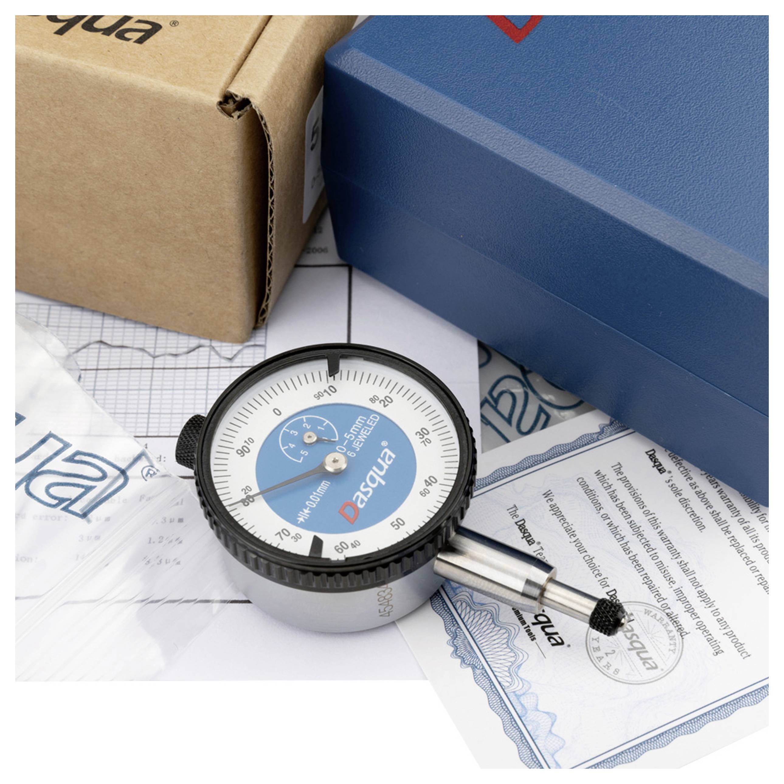 Mjerni uređaj za očitavanje milimetarskih vrijednosti leži na kartonu, pored njega plava ambalaža i certifikat s logotipom.