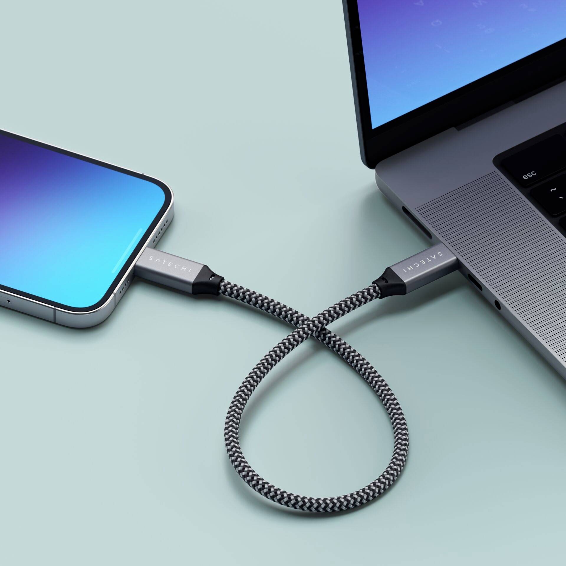 Smartphone i laptop povezaniupletenem kabelom koji omogućava prijenos podataka između uređaja.