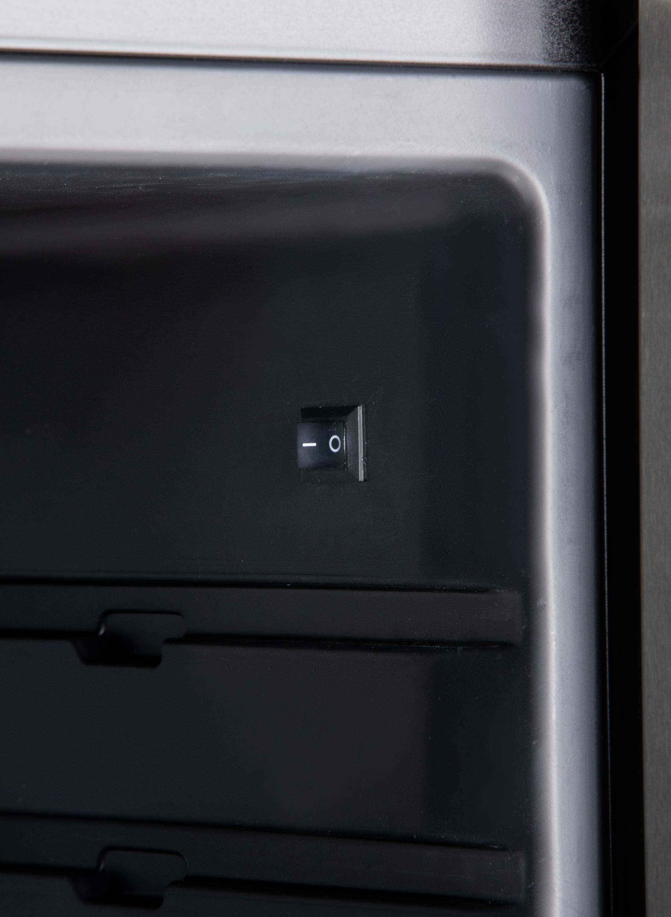 Crni mrežni prekidač s simbolima 'I' za uključeno i 'O' za isključeno, pričvršćen na metalnom uređaju. U pozadini: tamna površina.