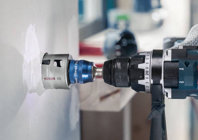 Bušilica sa kružnom pilom buši rupu u zidu; bliski kadar prikazuje precizno rukovanje; kontekst DIY ili građevinskih radova.