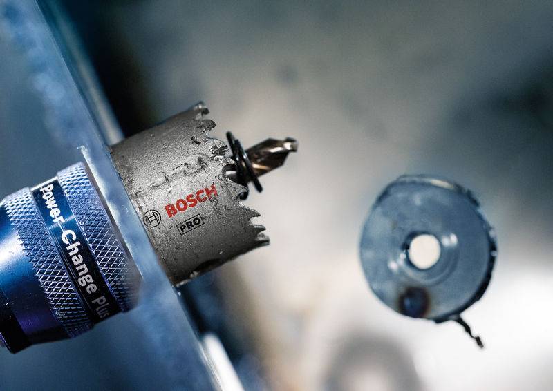 Bušni alat koji izrezuje okrupu rupu u komad metala, s nastavkom 'Bosch Pro'.