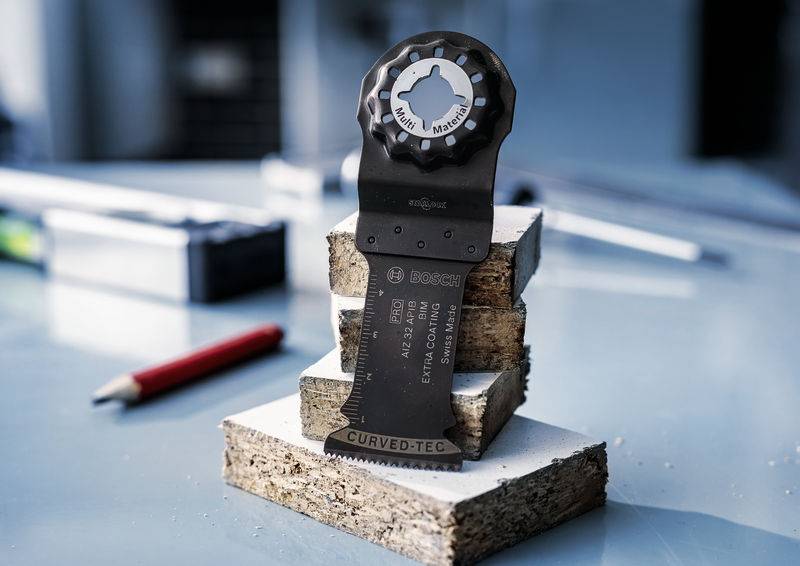 List pile na složenom drvu, u svijetloj okolini radionice s nejasnim crvenim olovkom u pozadini.