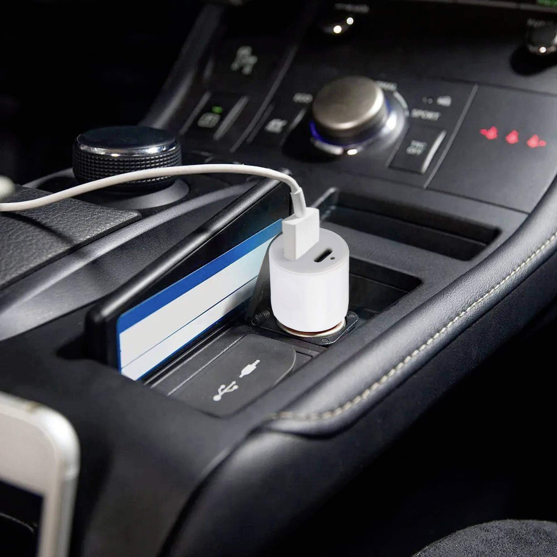 Automobilska armaturna ploča s punjačem u utičnici za upaljač. Bijeli USB kabel povezuje pametni telefon. Pretinac sadrži kreditnu karticu i ključeve.