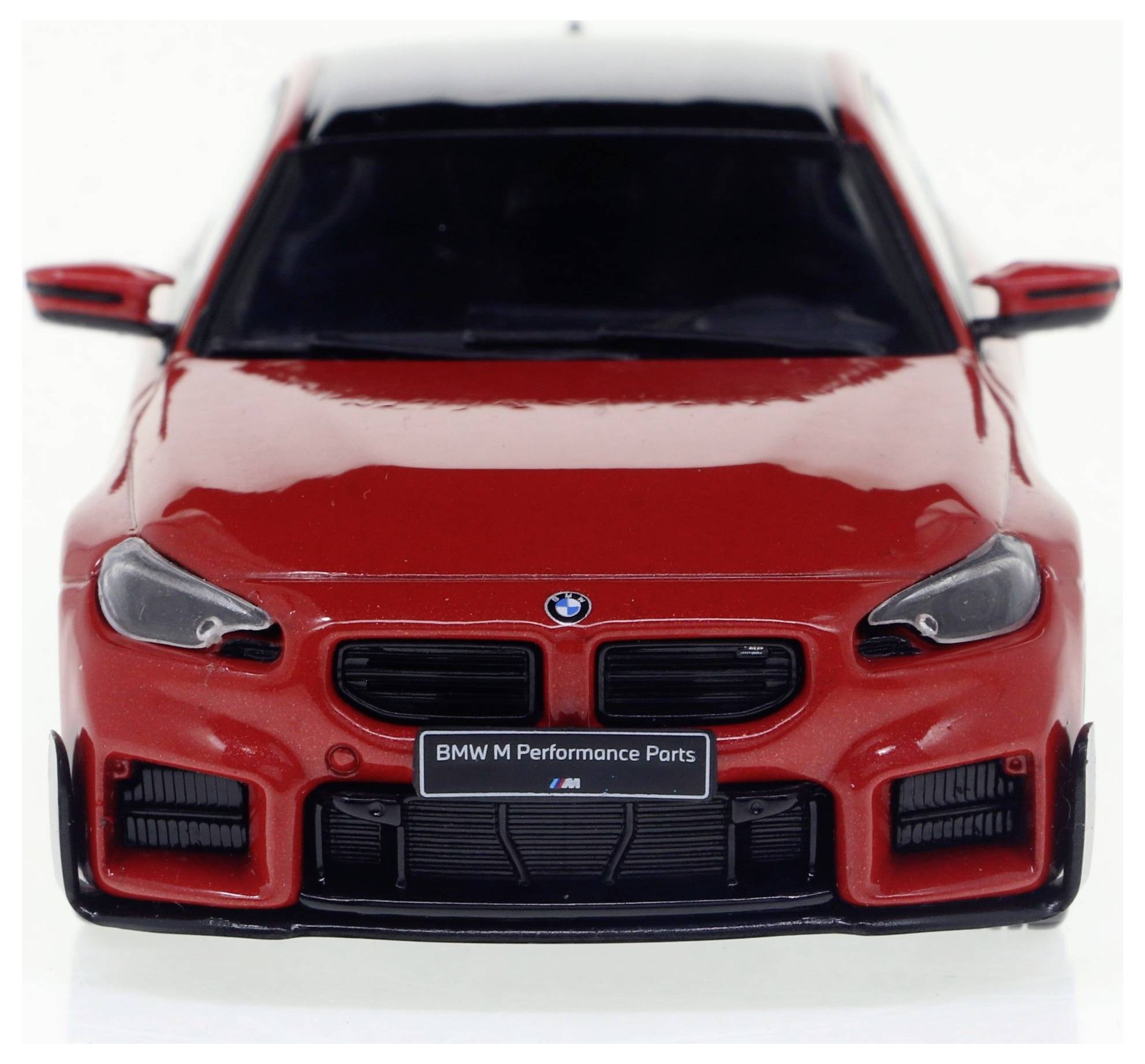 Crveni BMW s "BMW M Performance Parts" emblemom. Pogled na vozilo spreda, fokus na dizajnu i marki.