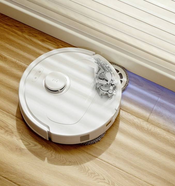 Okrugli usisni robot čisti drveni pod u dobro osvjetljenom prostoru.