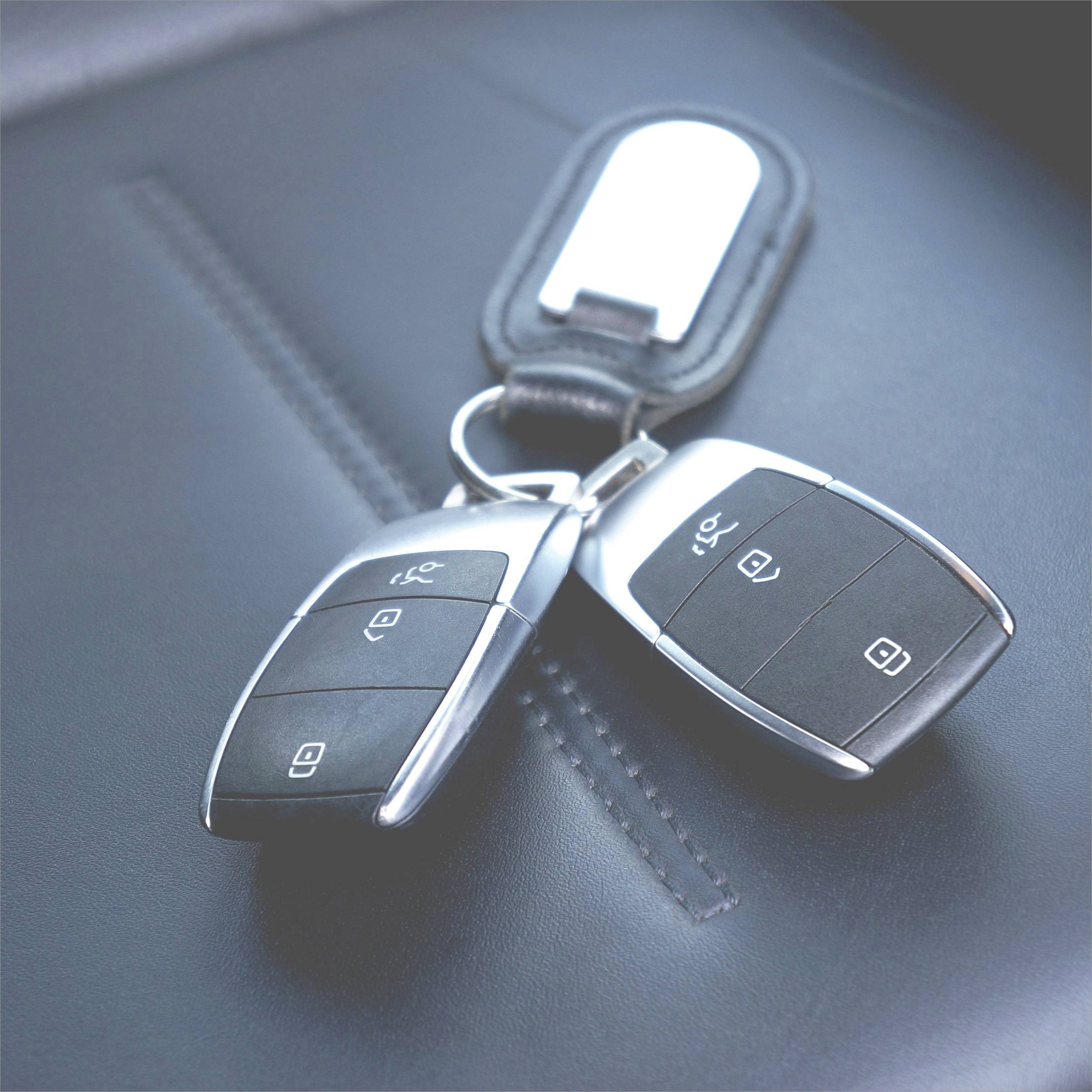 Dva ključa automobila leže na kožnatom sjedalu.