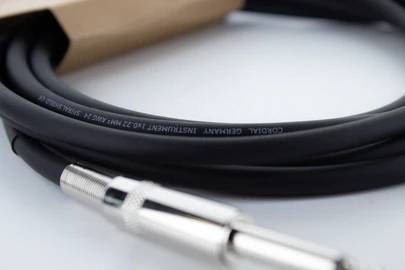 Crni audio kabel sa srebrnim utikačem na bijeloj pozadini, tiskani natpis: 'CORDIAL', broj modela i specifikacije.