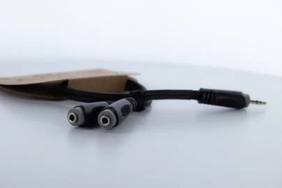 Jedan audio kabel račva se na dva 3,5-mm priključka na bijeloj podlozi.