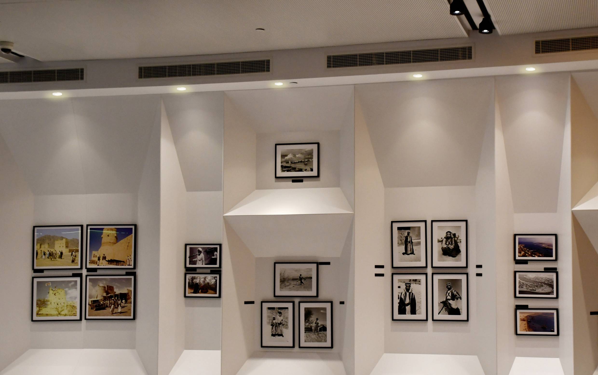 Zidna galerija umjetnosti koja prikazuje uokvirene fotografije različitih veličina u modernom, dobro osvjetljenom prostoru.