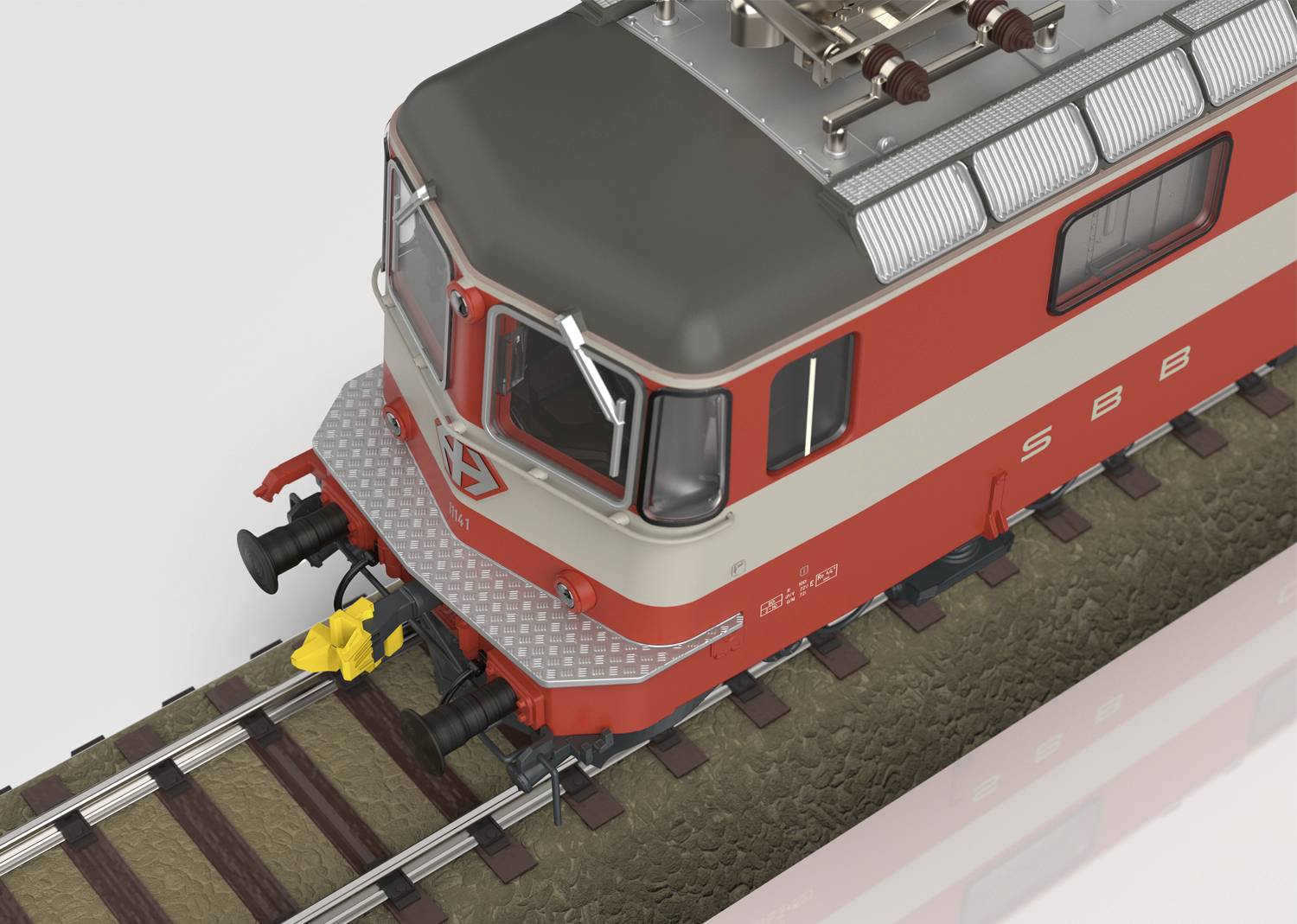 Crvena i siva lokomotiva SBB-a na segmentu tračnica, pogled odozgo, s tipičnim željezničkim elementima poput odbojnika i kvačila.