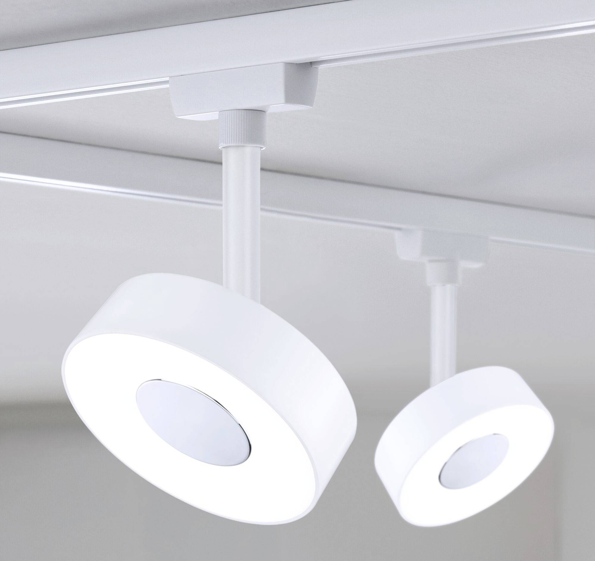 Dvije moderne, bijele stropne lampe pričvršćene su na šinu. Okruglog su oblika s centralnim elementom osvjetljenja i osvjetljavaju prostor.