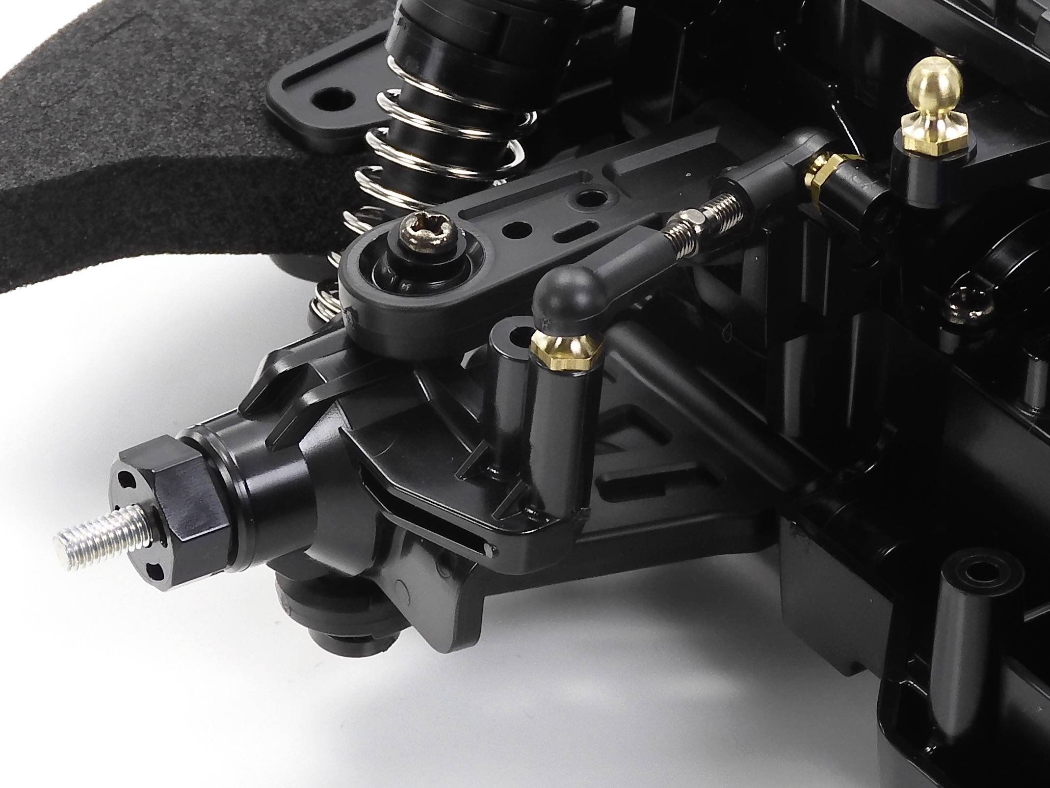 Close-up snimka RC auto suspenzijskog sustava s oprugama, amortizersima i kuglastim zglobovima koji prikazuju detalje mehanike.