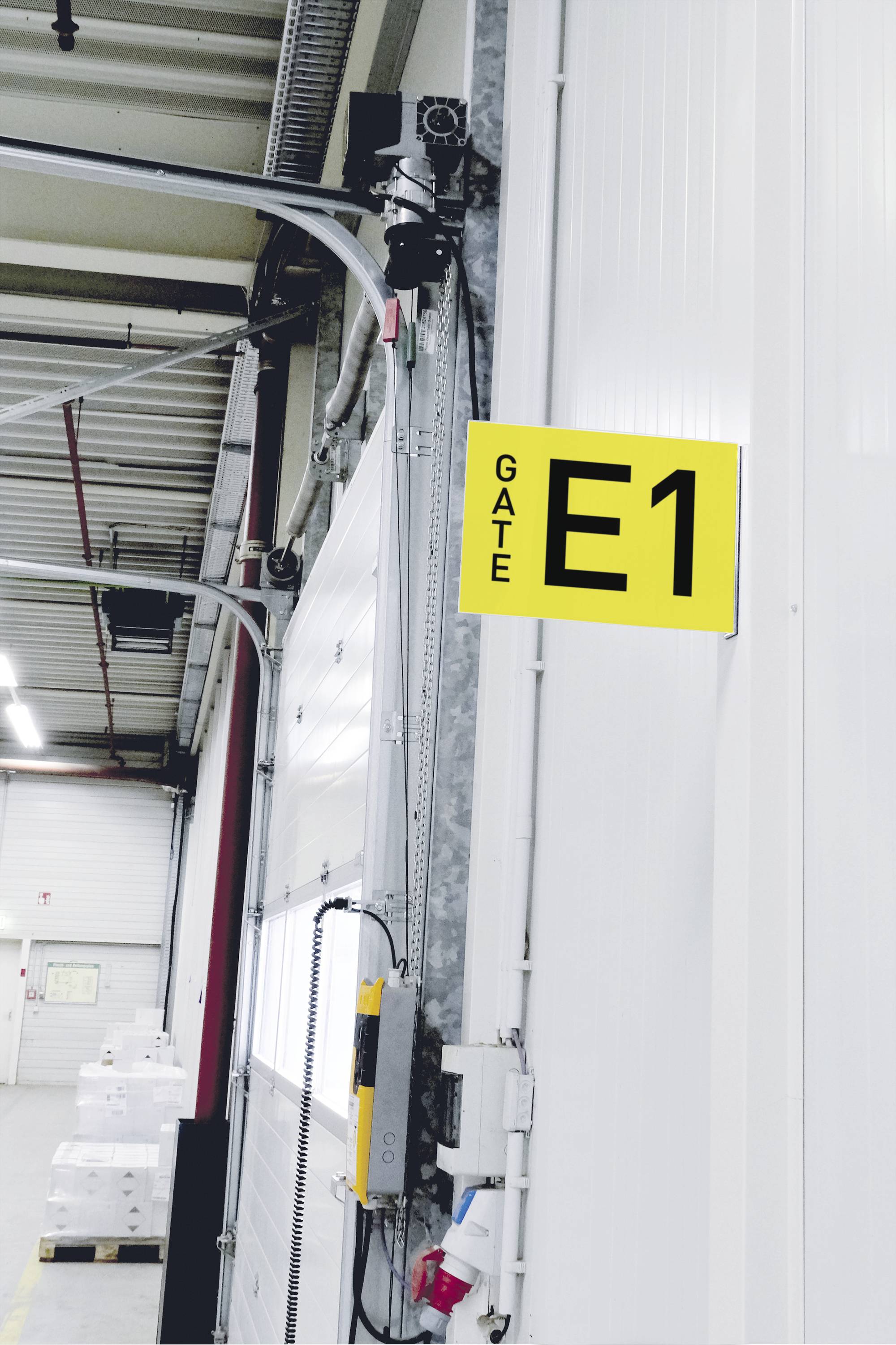 Natpis 'Tor E1' na industrijskim vratima u skladištu.