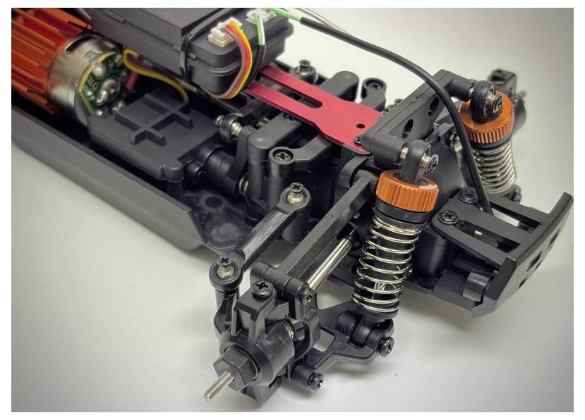 Detaljan pogled na sustav suspenzije radio-vođenog automobila, koji prikazuje detaljne opruge, amortizere i motorske komponente, ističući mehaničku složenost.