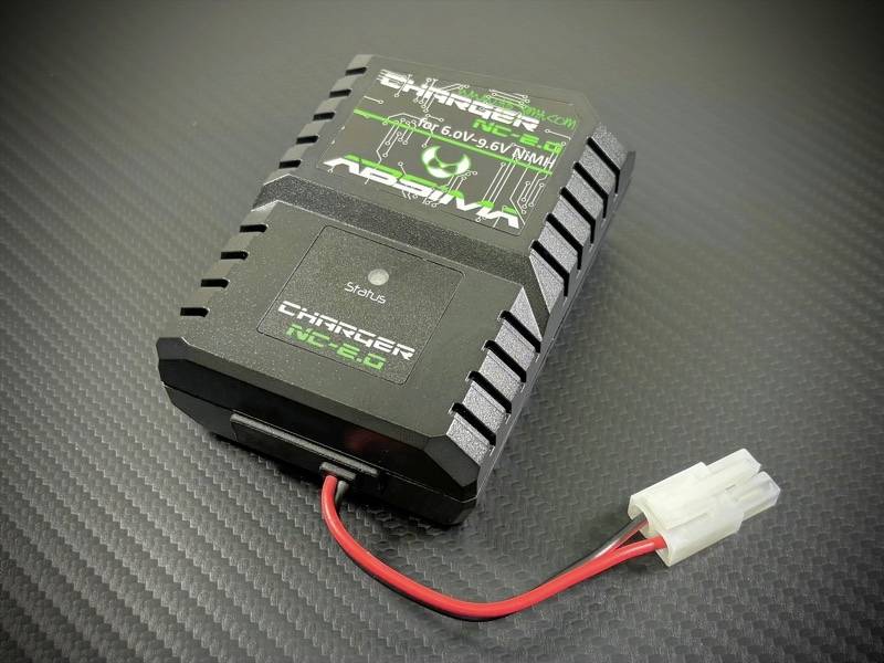 Crni punjač za NiMH baterije od 6,0 do 9,6 V postavljen na tamnoj podlozi. Ima crvene i bijele priključne kablove.