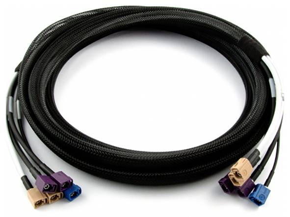 Crni, okrugli kabel s više obojenih utikača na oba kraja leži smotан na bijeloj površini.
