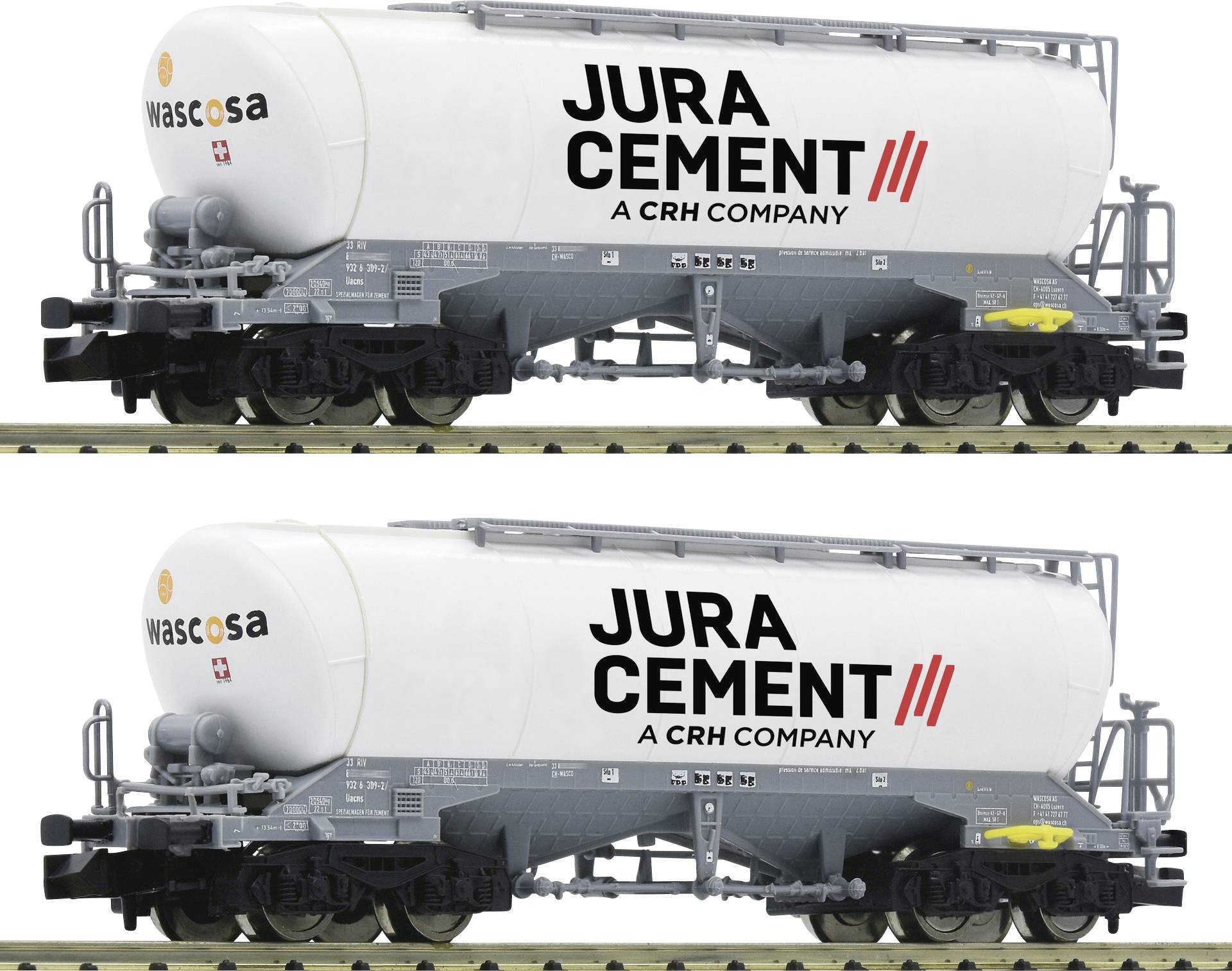 Dva cementa vagona s natpisima 'Jura Cement - CRH kompanija' i 'Wascosa' na bokovima, stojeći na tračnicama.