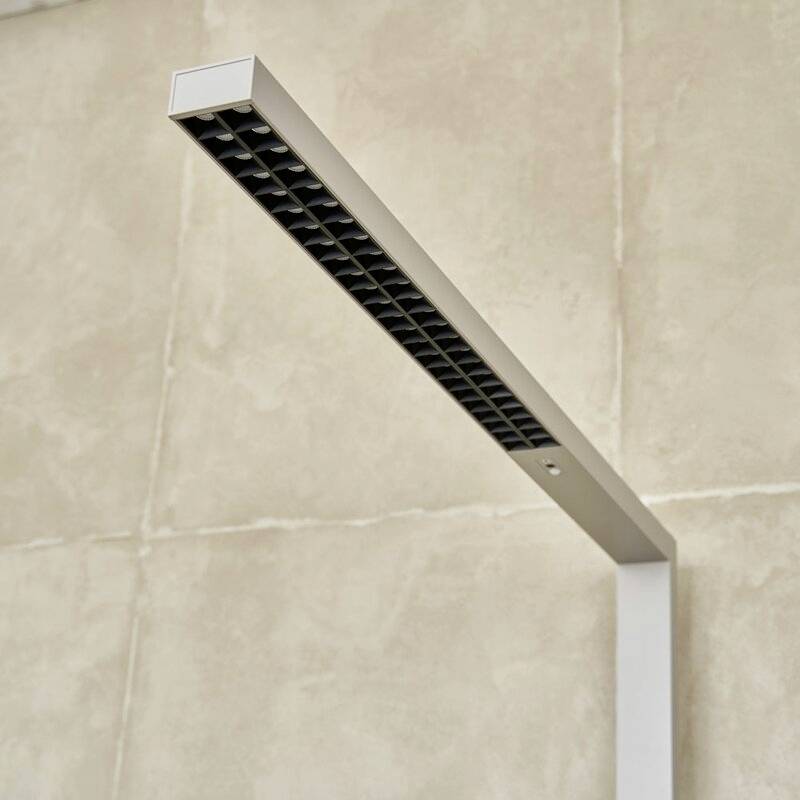 Moderna, minimalistička LED svjetiljka s crnim rešetkastim dizajnom, montirana na bež zid.