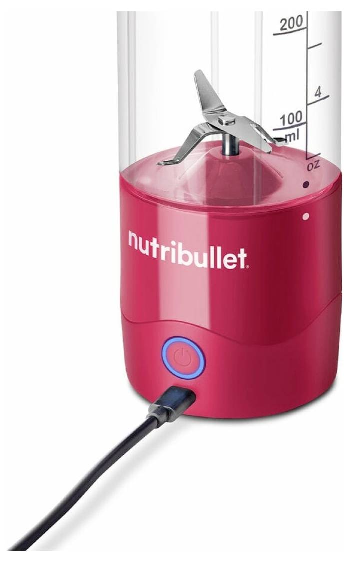 Crveni Nutribullet blender s vidljivom tipkom za uključivanje i mjernom ljestvicom do 200 ml sa strane. Blender je uključen u struju.