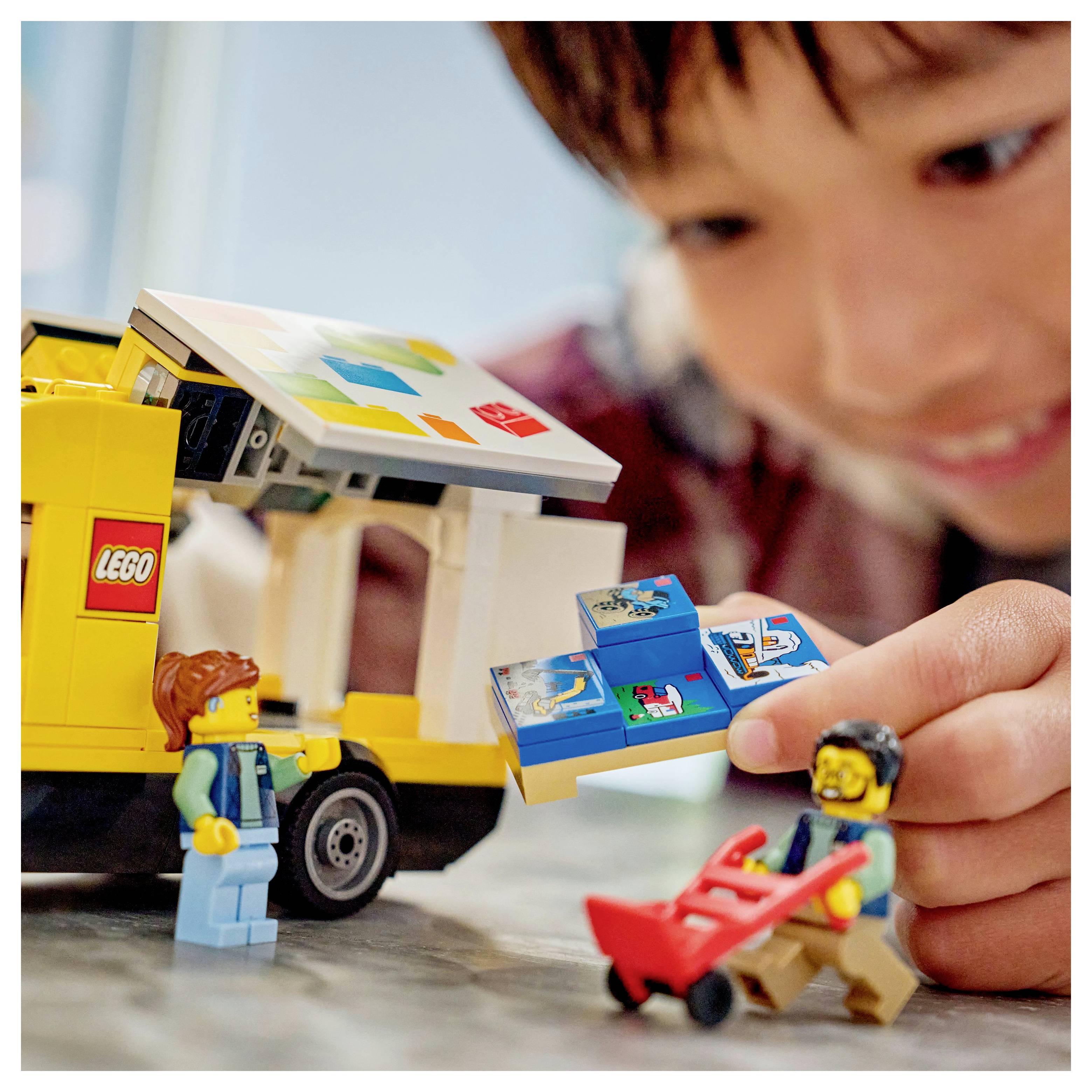 Dijete se igra s igračkom dostavnom kamionom i figurama, sudjelujući u imaginativnoj igri, prikazujući kreativnost i istraživanje kroz igru uloga.