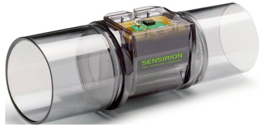 Prozirna cijev protočnog senzora s elektronikom označenom 'SENSIRION' u sredini, koja se koristi za mjerenje protoka plina ili tekućine.