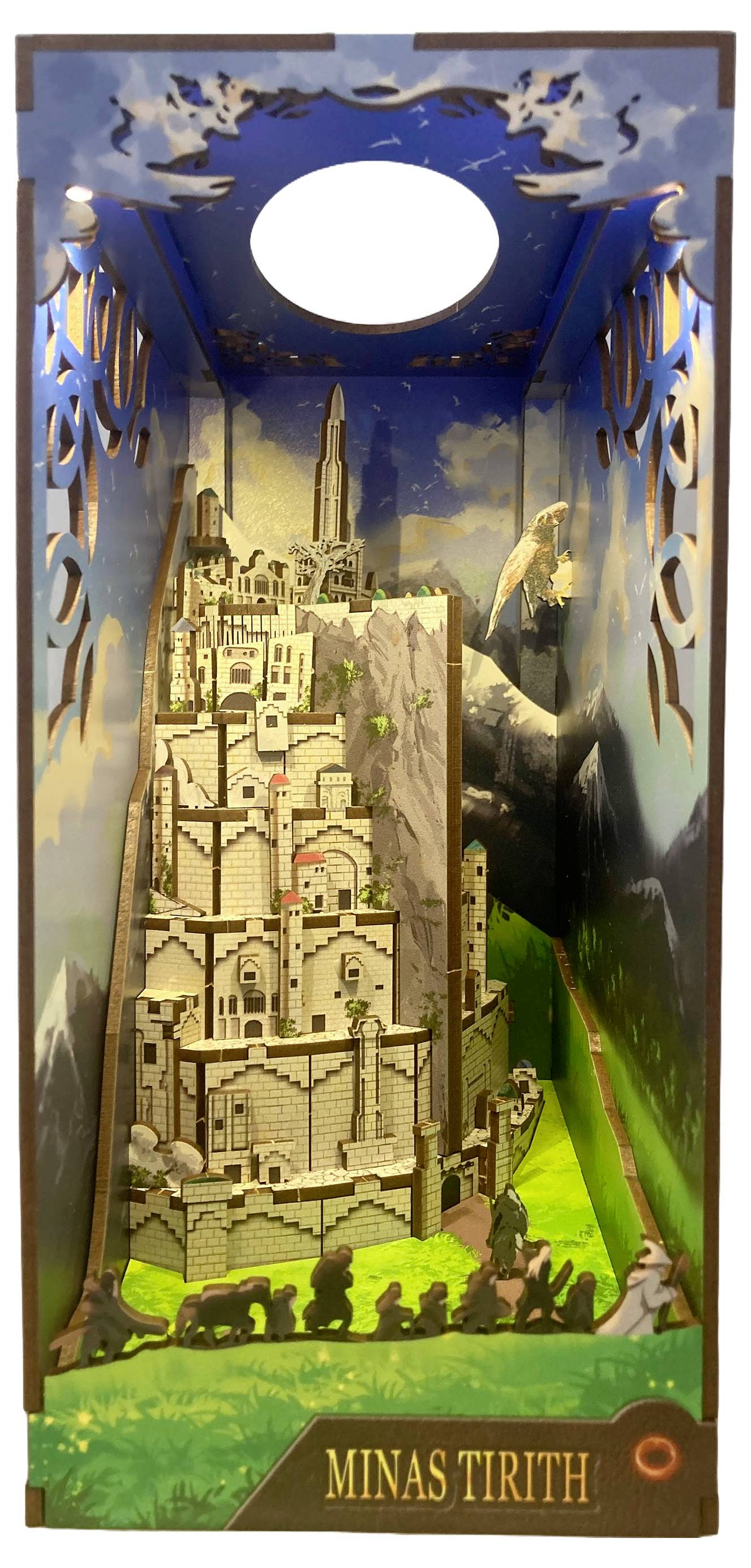 Diorama 'Minas Tirith' prikazuje detaljan model planinskog, višeslojnog grada sa zidinama i kulama, postavljenog ispred pozadine neba.