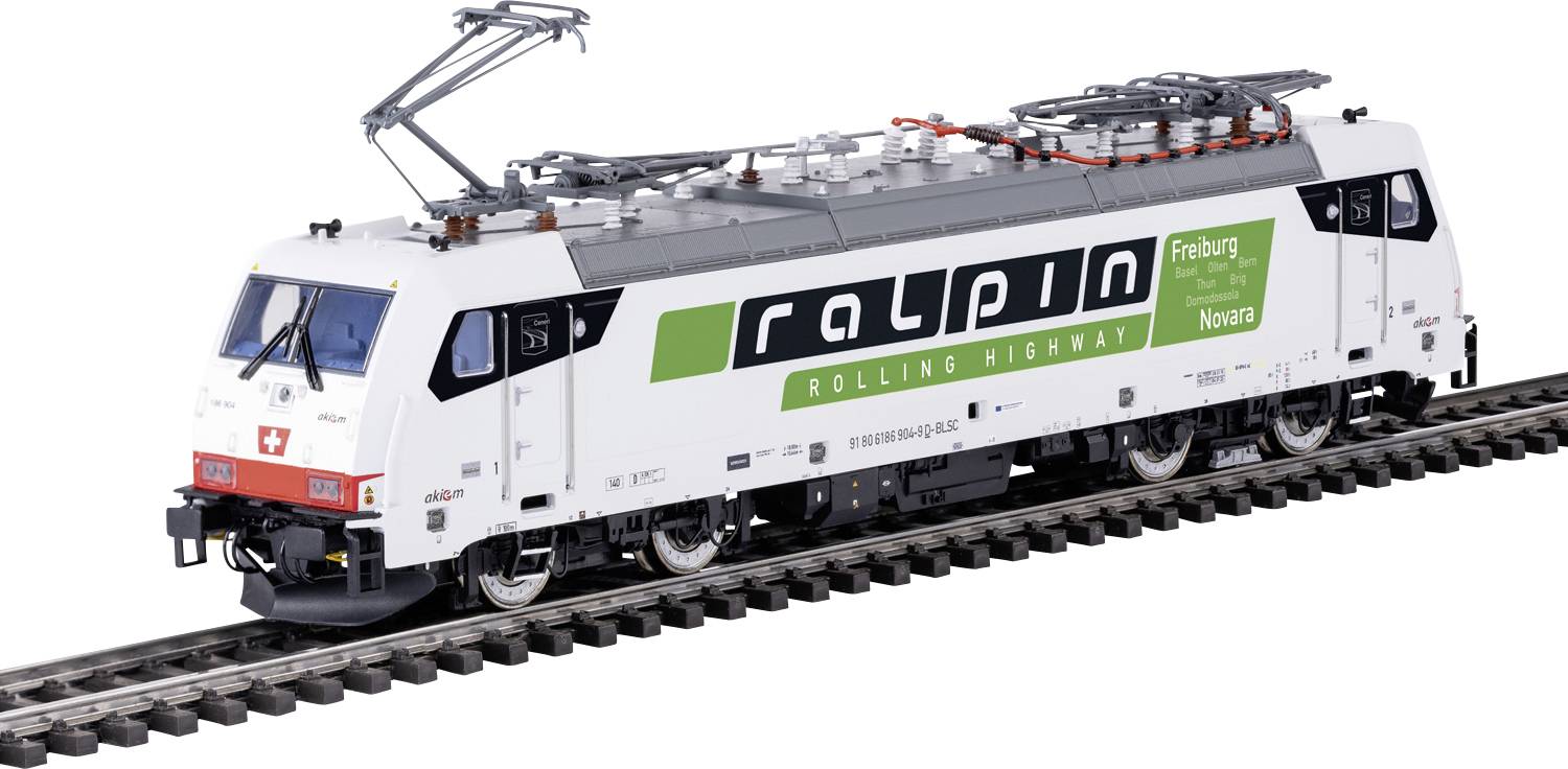 Bijela lokomotiva na željezničkim tračnicama s logom 'ralpin' i tekstom 'Rolling Highway'. Opremljena je pantografom na vrhu.