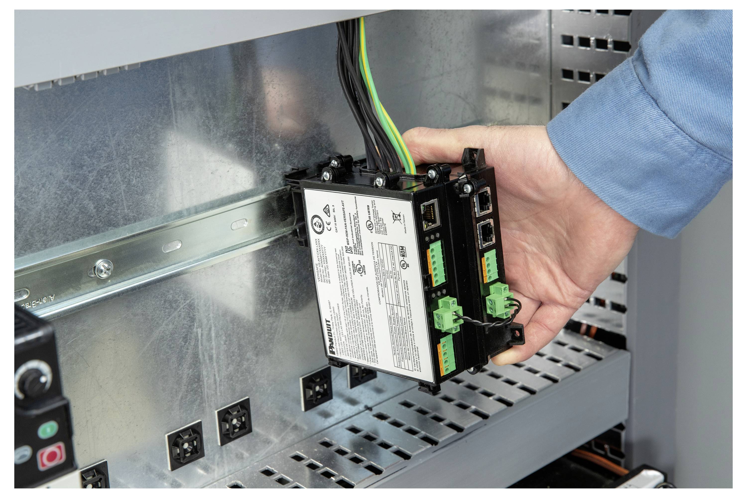 Ruka instalira industrijski elektronički modul na metalnu sabirnicu unutar kontrolnog ormarića.