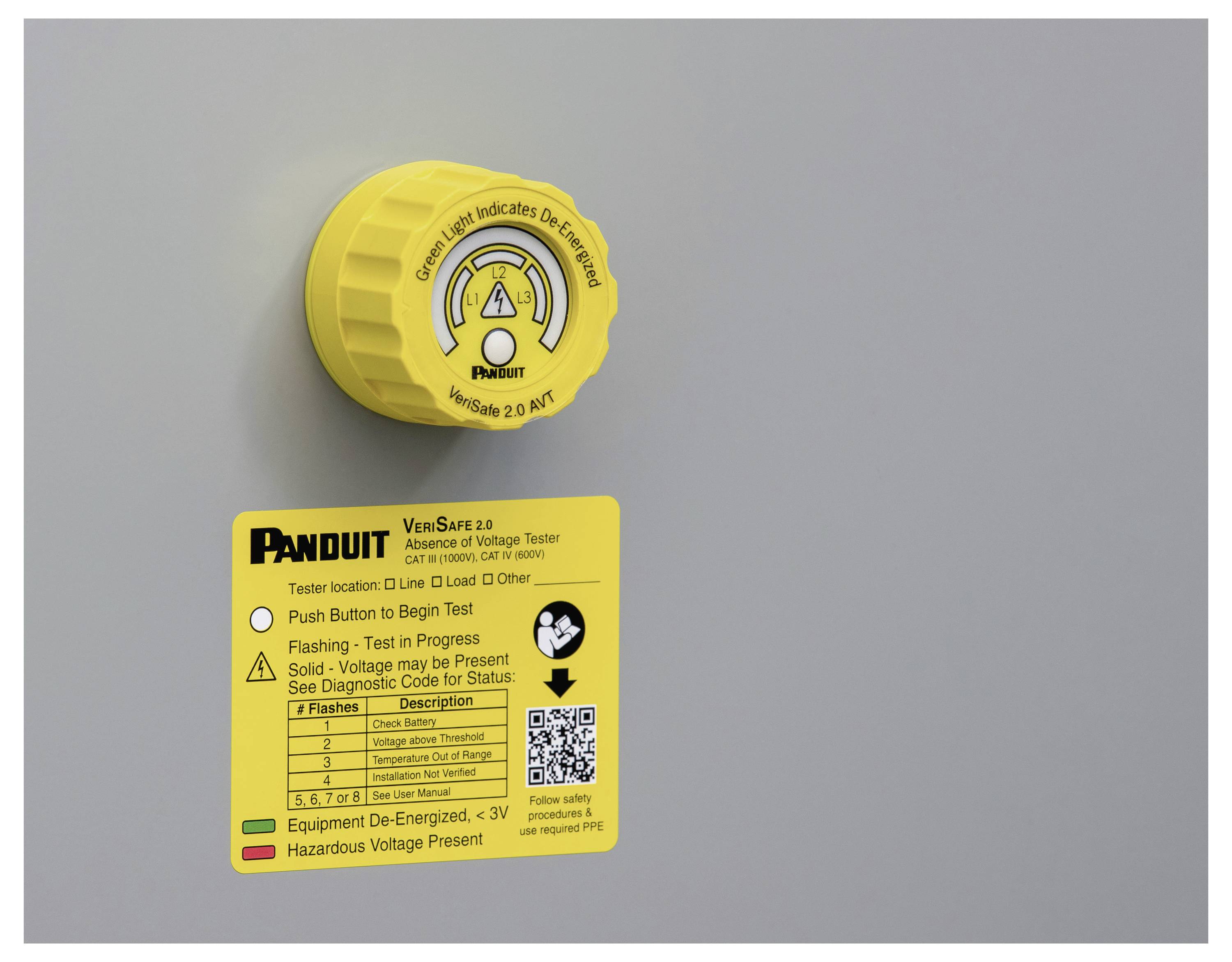Poklopac i upute za naponski tester 'Panduit VeriSafe 2.0' na sivoj površini, ističući korake za testiranje električne sigurnosti.