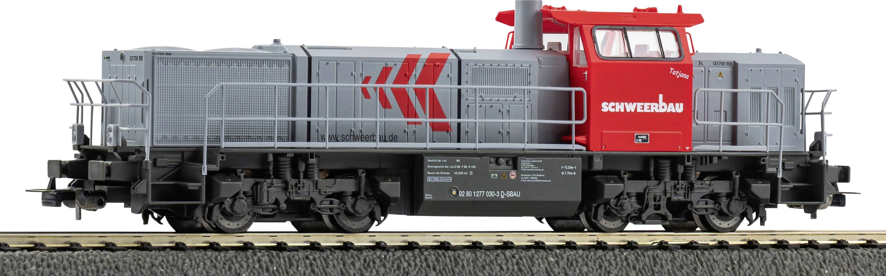 Model lokomotive za igračke u sivoj i crvenoj boji sa logotipom 'SCHWERER' na boku, na prikaznoj trati, pokazujući detaljne komponente tračnica i kotača.