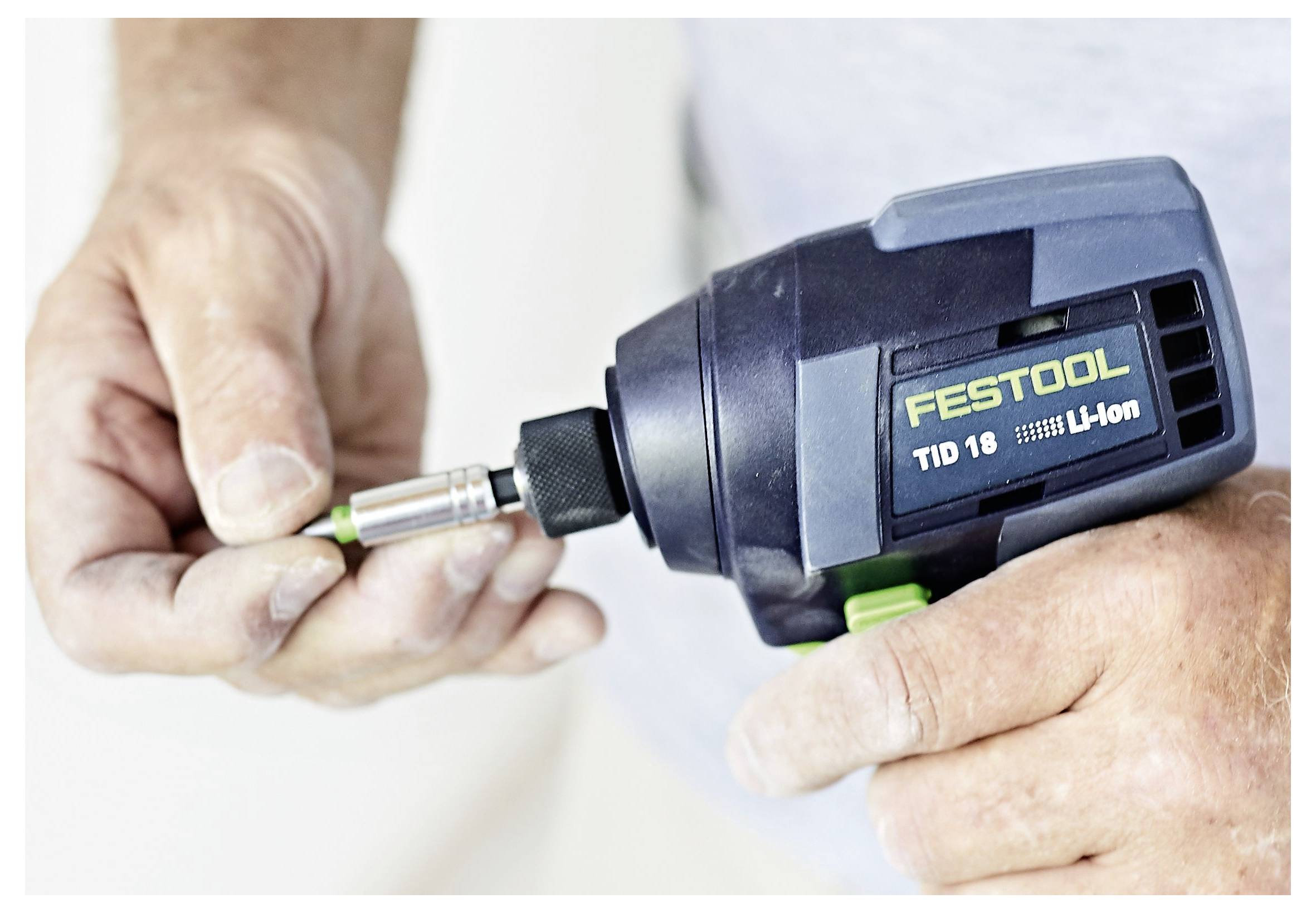 Osoba umeće svecu u bušilicu Festool TID 18 Li-Ion bez žice, veliki plan ruku i bušilice.